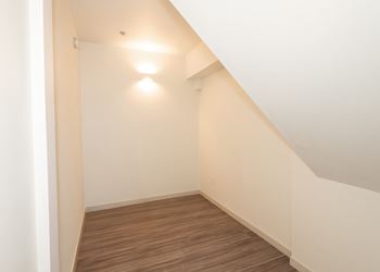 A hallway with wooden floors and white walls.